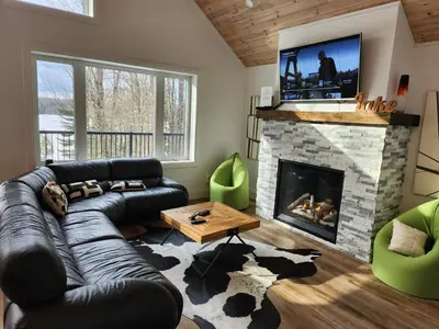 a living room with a black leather couch and a fireplace at The Hidden Pearl in Haliburton