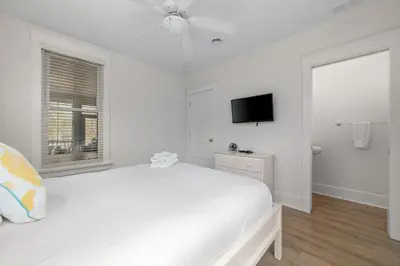 a white bedroom with a white bed and a tv at L'Hibou - 18 Farm View in Cherry Valley