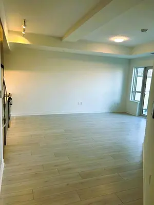 an empty room with white walls and wood floors at Stunning new condo in Oakville in Oakville