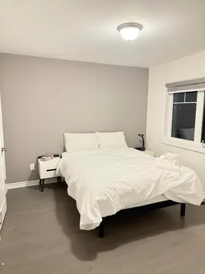 a white bedroom with a large bed and a window at 4-Bdrm Comfort with Fireplace mins from Downtown in Port Colborne