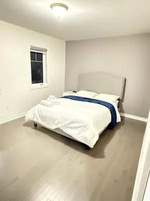 a bedroom with a bed with white sheets and a window at 4-Bdrm Comfort with Fireplace mins from Downtown in Port Colborne