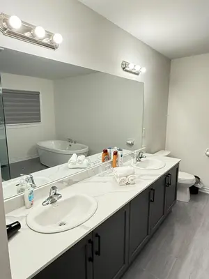 a bathroom with two sinks and a large mirror at 4-Bdrm Comfort with Fireplace mins from Downtown in Port Colborne
