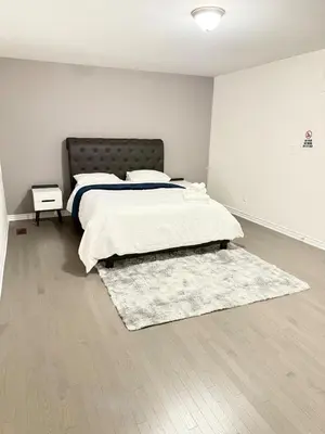 a white bedroom with a bed and a rug at 4-Bdrm Comfort with Fireplace mins from Downtown in Port Colborne