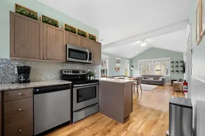 a kitchen with stainless steel appliances and a living room at The Hemlock - 1 Hollow in Cherry Valley