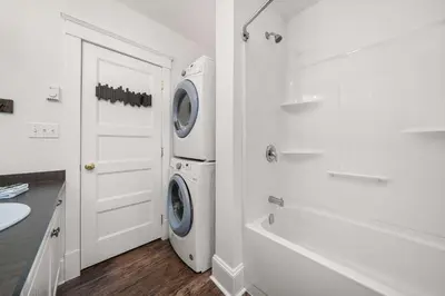 a white bathroom with a washing machine and a sink at The Trillium - 2 Pine Forest in Cherry Valley