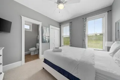 a bedroom with a large white bed and a bathroom at The Rushes - 47 Butternut in Cherry Valley