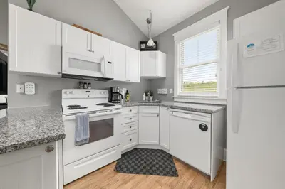 a white kitchen with white appliances and a window at The Rushes - 47 Butternut in Cherry Valley