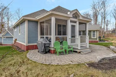 a house with two green chairs on a patio at The Cedar - 6 Hollow in Cherry Valley