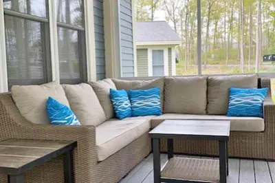 a couch sitting on a porch with blue pillows at The Cedar - 6 Hollow in Cherry Valley