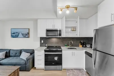 a kitchen with white cabinets and a blue couch at Luxury Spacious Apartment 10 min to Airport Wifi in Brampton