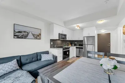 a living room with a couch and a table and a kitchen at Luxury Spacious Apartment 10 min to Airport Wifi in Brampton