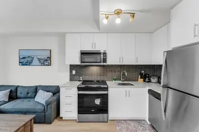 a kitchen with white cabinets and a blue couch at Luxury Spacious Apartment 10 min to Airport Wifi in Brampton