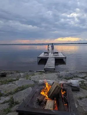 two people are standing on a dock over a fire at Comfy Waterfront Suite 2 Double Beds Ensuite in Belleville