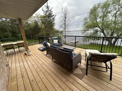 a wooden deck with couches and chairs on it at Guest Suite w Ensuite Waterfront in Belleville