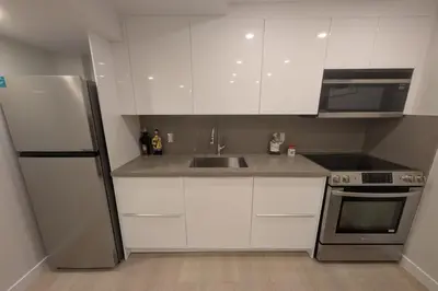 a kitchen with white cabinets and a stainless steel refrigerator at Elegant & Stylish Apartments with Private Entrance & Parking in Richmond Hill