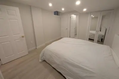 a white bedroom with a large white bed in it at Elegant & Stylish Apartments with Private Entrance & Parking in Richmond Hill