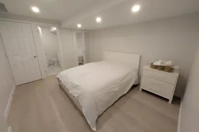 a white bedroom with a bed and a bathroom at Elegant & Stylish Apartments with Private Entrance & Parking in Richmond Hill