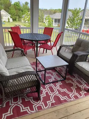 a screened in porch with chairs and a table and tables at The Phoebe - 65 Butternut in Cherry Valley