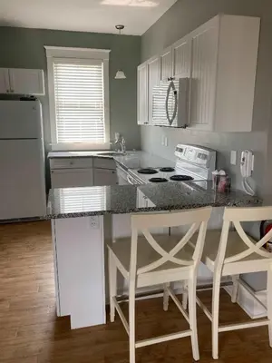 a kitchen with white cabinets and a counter with stools at The Phoebe - 65 Butternut in Cherry Valley