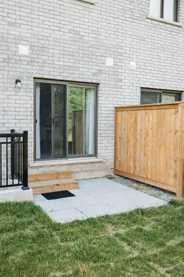 a wooden bench next to a building with a fence at Luxury Living 5 mins from the Falls in Niagara Falls