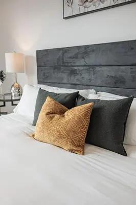 a bedroom with a white bed with black pillows at Luxury Living 5 mins from the Falls in Niagara Falls