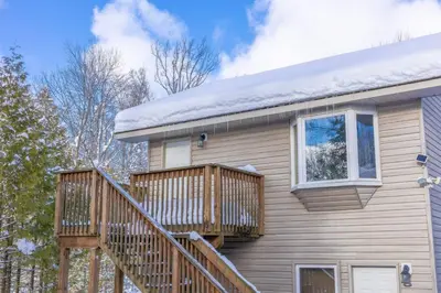 a house with a deck with snow on it at Lake View Loft in Severn