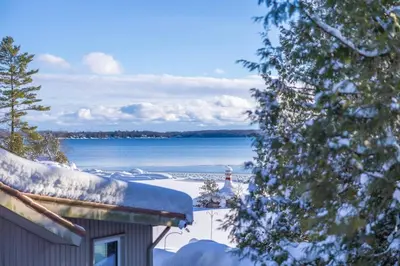 a house with a lighthouse in the snow next to a lake at Lake View Loft in Severn