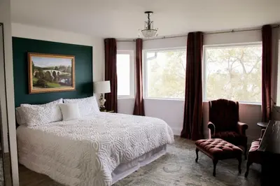 a bedroom with a bed and a chair and windows at Large Waterfront Home w 5 Ensuite Bathrooms in Belleville