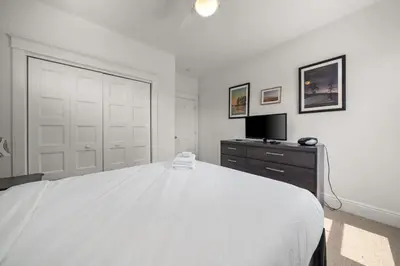 a white bedroom with a large bed and a television at The Marmot - 12 Butternut in Cherry Valley