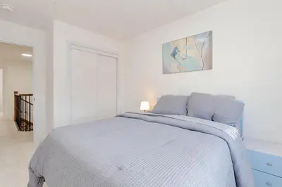 a white bedroom with a bed with a blue blanket at Amazing Home in Niagra Region in Thorold