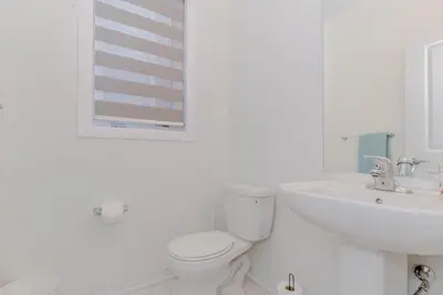 a white bathroom with a toilet and a sink at Amazing Home in Niagra Region in Thorold