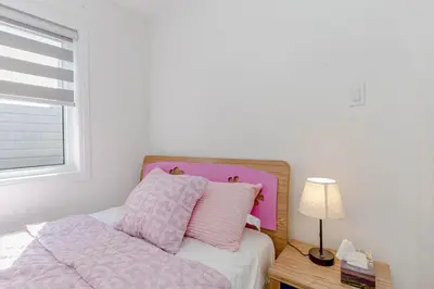 a bed with pink and white sheets and a table with a lamp at Amazing Home in Niagra Region in Thorold