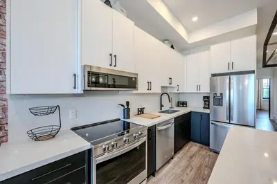 a kitchen with white cabinets and stainless steel appliances at Charming 2 Bed Apartment in Cambridge