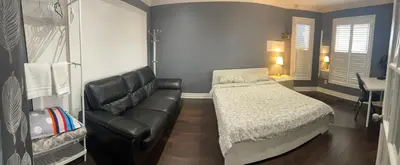 a bedroom with a bed and a leather couch at F1 cozy Sunny room in Mississauga