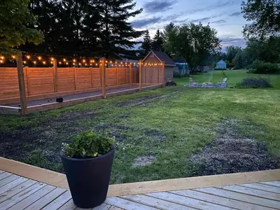 a backyard with a fence with lights on it at Park and Mill - Hot Tub and Bocce Court in Bloomfield