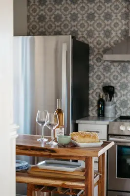 a kitchen with a table with wine glasses and a plate of food at Park and Mill - Hot Tub and Bocce Court in Bloomfield