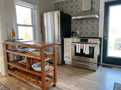 a kitchen with a stove and a refrigerator and a table at Park and Mill - Hot Tub and Bocce Court in Bloomfield