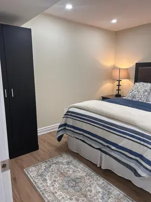 a bedroom with a bed and a black cabinet at Private 2bedroom Unit, Free Parking, Free from Smoke & Pet, Self-Check IN in Pickering