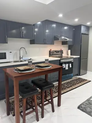 a kitchen with a wooden table and black cabinets at Private 2bedroom Unit, Free Parking, Free from Smoke & Pet, Self-Check IN in Pickering