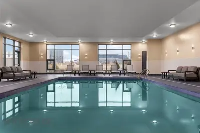 a swimming pool in a hotel with chairs and tables at Hyatt Place Mississauga / Airport Corp Center in Mississauga