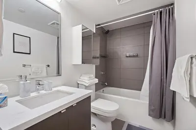 a white bathroom with a sink and a toilet and a tub at Luxurious Suite in Yorkville in Toronto