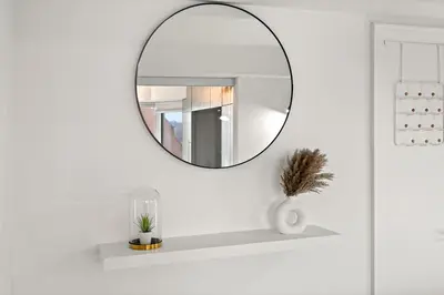 a mirror hanging on a white wall with a shelf at Luxurious Suite in Yorkville in Toronto