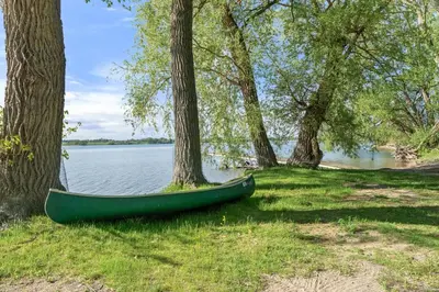 a green canoe sitting on the grass next to trees at The Amanita - 9 Hollow in Cherry Valley
