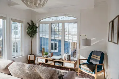 a living room with a couch and a table and windows at Marina and Main - In Ground Pool and Games Room in Wellington