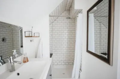 a white bathroom with a sink and a mirror at Marina and Main - In Ground Pool and Games Room in Wellington