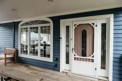 a blue house with white doors and a chair at Marina and Main - In Ground Pool and Games Room in Wellington