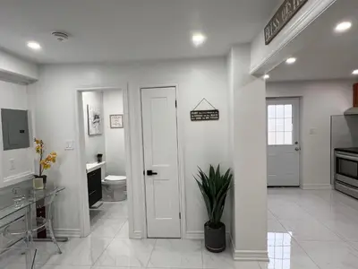 a white bathroom with a toilet and a door at St Catharines Niagara Escape in St. Catharines