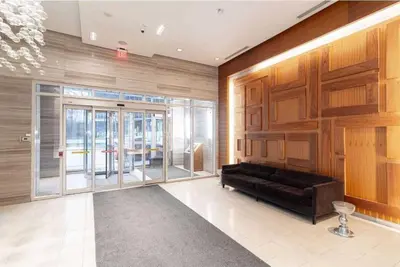 a living room with a black couch and a glass door at Belarte Suites - Downtown Toronto - CN Tower & Rogers Centre in Toronto
