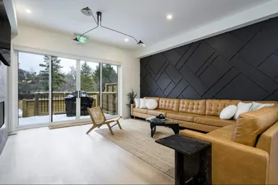 a living room with a brown couch and a black wall at The Luxury Black Rose Chalet at The Blue Mountains for 20 in Blue Mountains