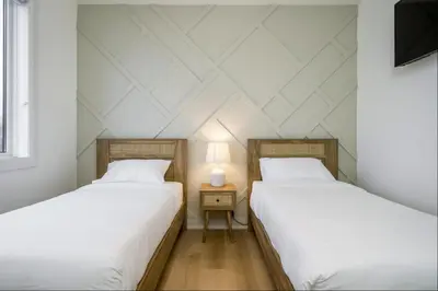 two beds in a room with white walls at The Luxury Black Rose Chalet at The Blue Mountains for 20 in Blue Mountains